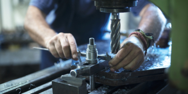 Worker operating industrial machine in metal workshop.
